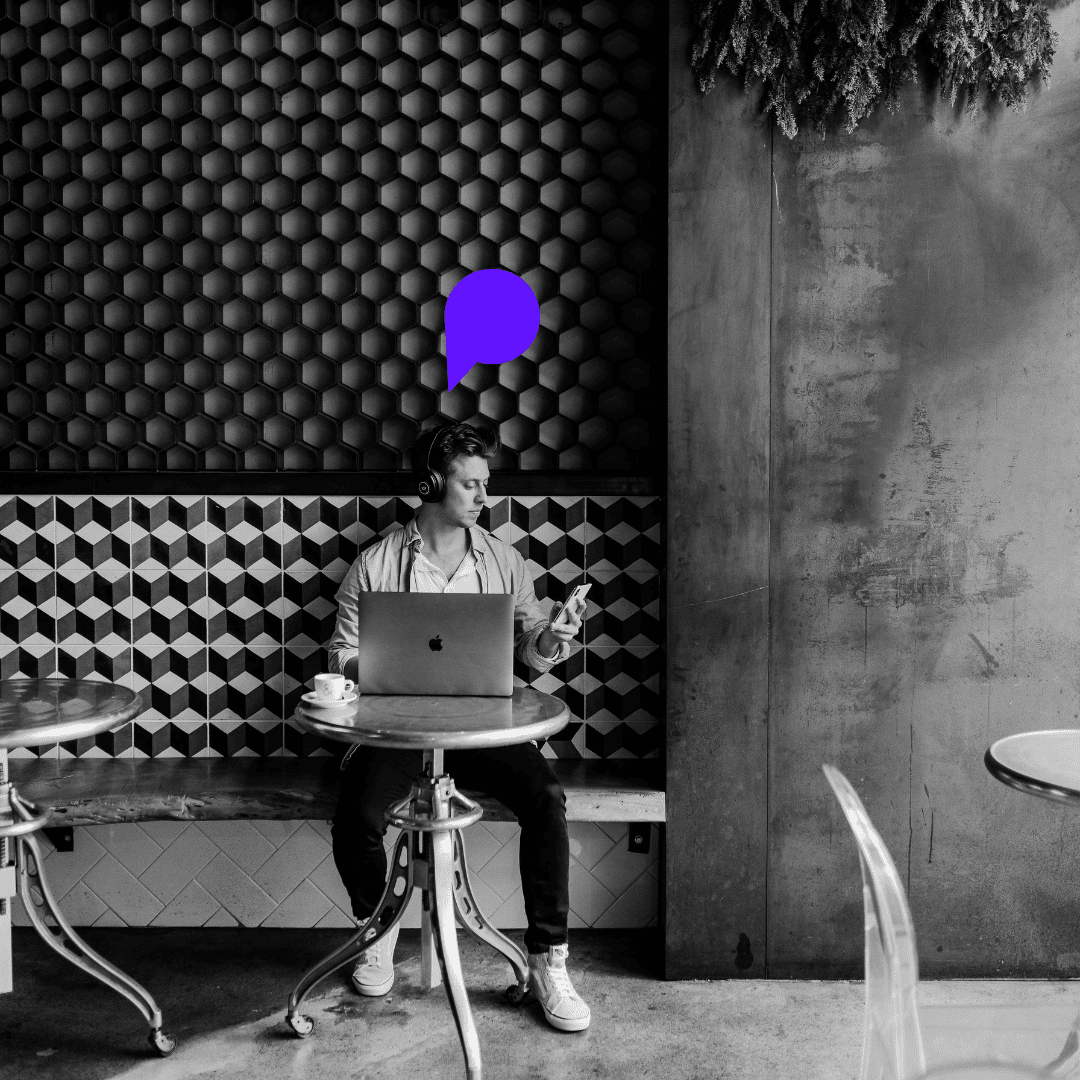 Un jeune auditeur en café, connecté à un podcast via son ordinateur, montrant l’intégration du contenu audio dans un cadre professionnel et quotidien.