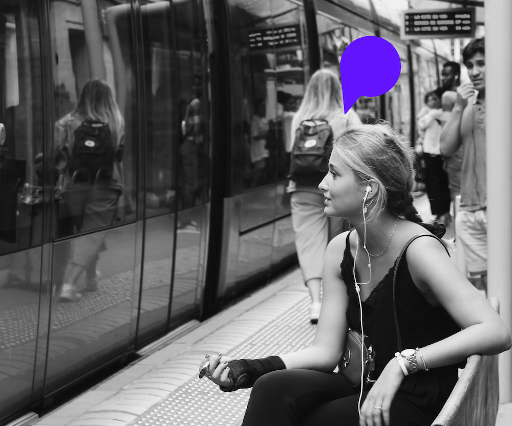 Une auditrice écoute un podcast dans une station de métro, illustrant la mobilité et l’immersion audio.
